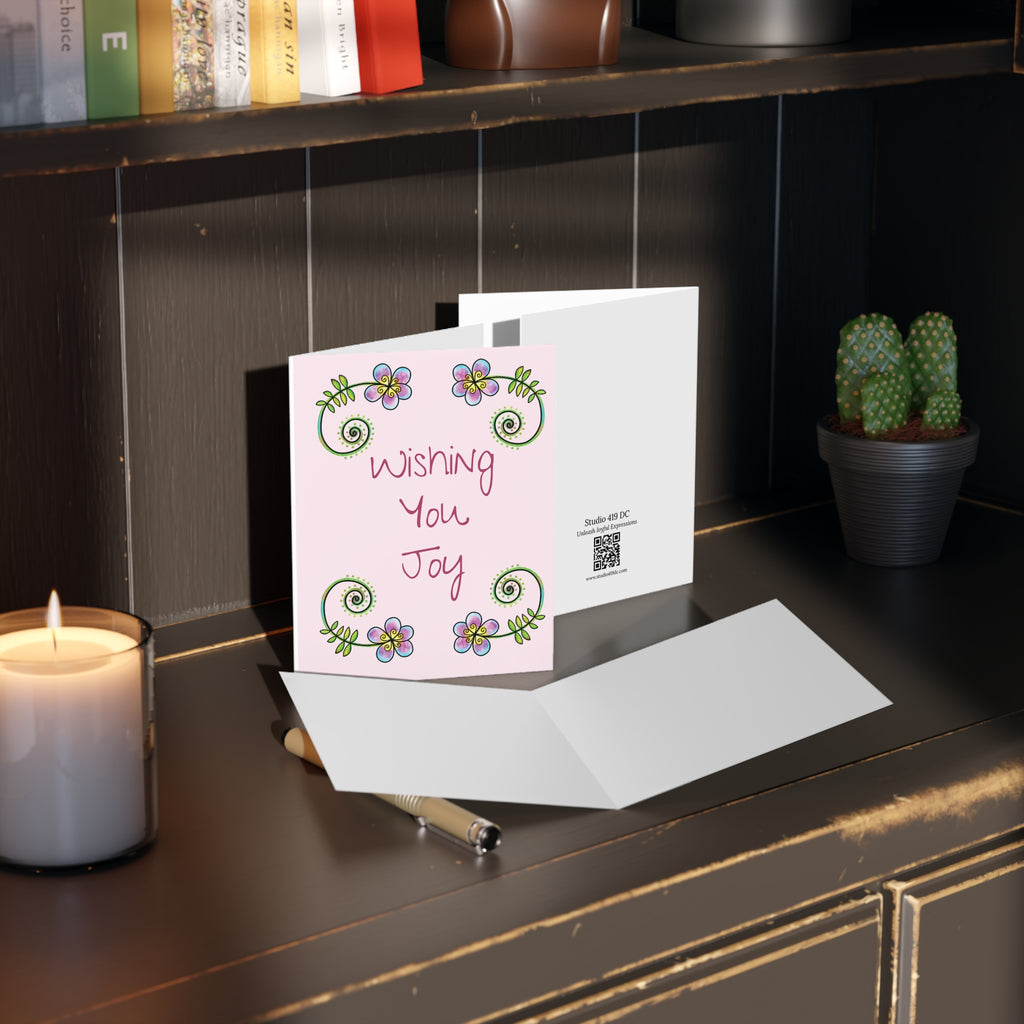 Wishing You Joy floral greeting card styled with envelope on desk